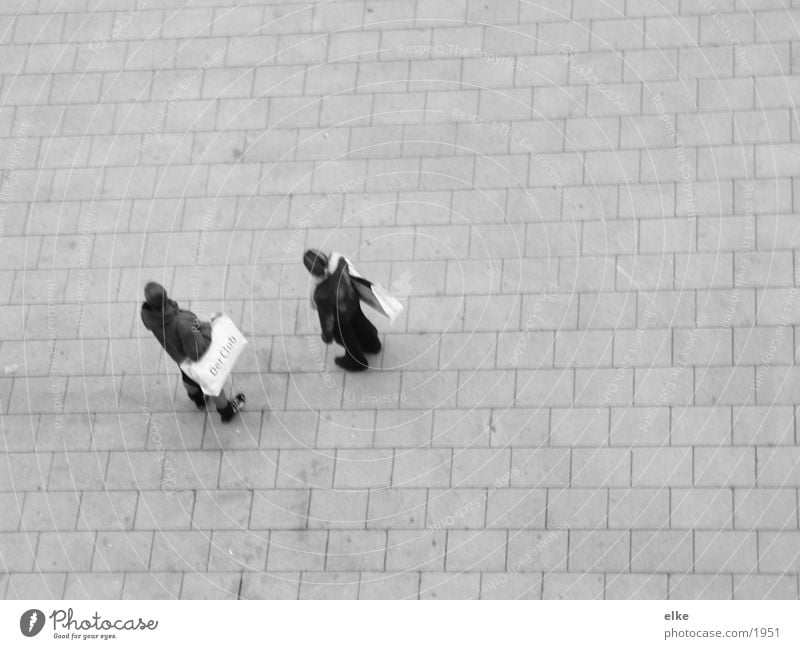 I wonder what's happening. Woman Paper bag Stand Cobblestones Observe Wait