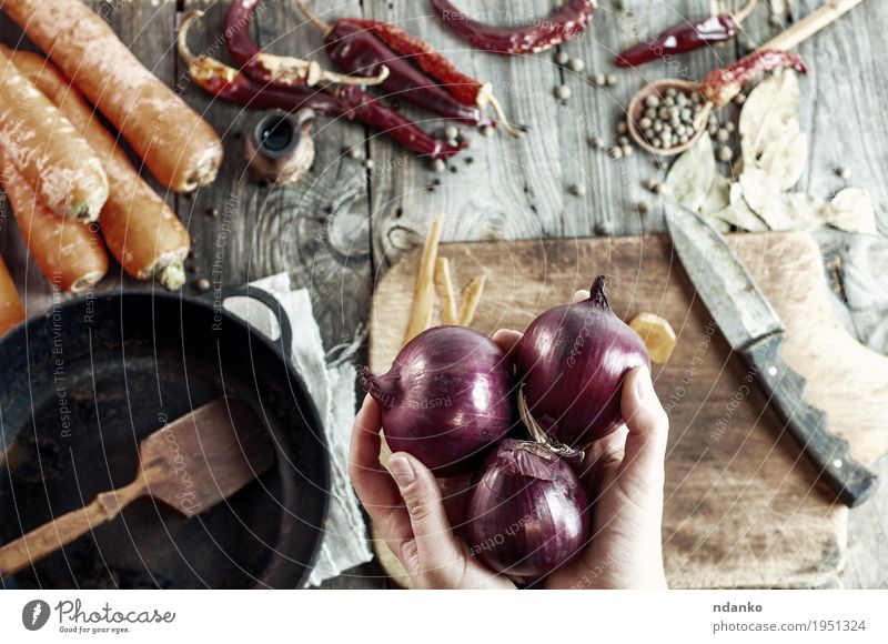 three large red onions in female hands Food Vegetable Herbs and spices Eating Vegetarian diet Pan Knives Spoon Table Cook Kitchen Woman Adults Hand Fingers