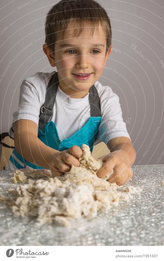 Little boy is kneading raw pizza dough and smiling Dough Baked goods Bread Joy Playing Kitchen Child Boy (child) Smiling Make Blue Delightful Apron Baking Baker
