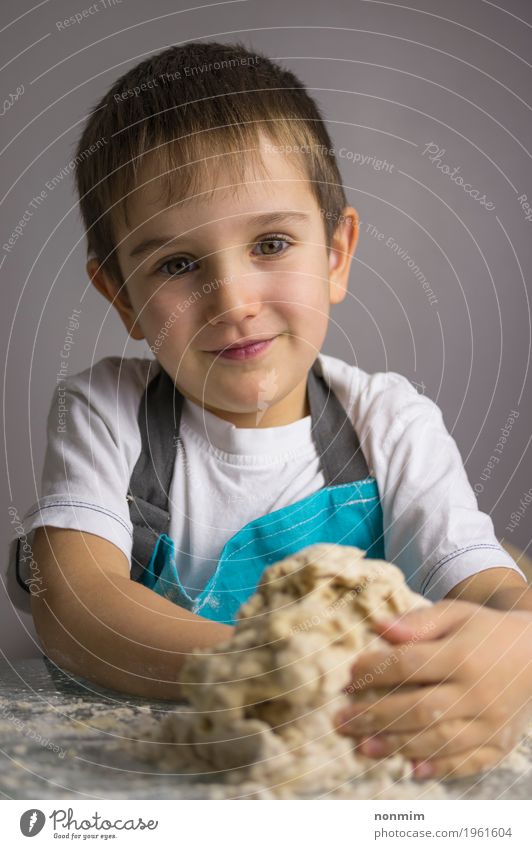 Little boy is kneading raw pizza dough and smiling Dough Baked goods Bread Joy Kitchen Child Boy (child) Infancy Smiling Make Blue Innocent Delightful Apron