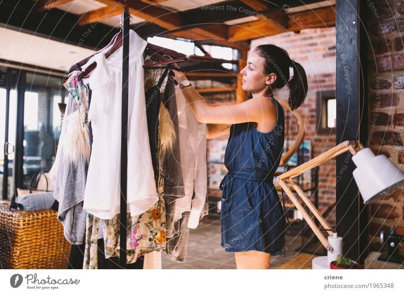 Young female designer hanging dresses on clothes rail Joy Work and employment Profession Office Factory Business SME Human being Feminine Young woman