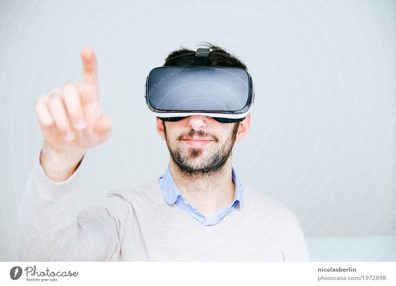 Medium adult man wearing virtual reality simulator glasses pointing finger and white background VR glasses Technology Forefinger Playing Computer games Smiling