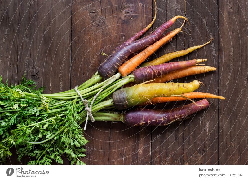 Fresh organic rainbow carrots with leaves on a wooden table Vegetable Nutrition Vegetarian diet Brown Yellow Carrot Farmer food Harvest healthy market orange