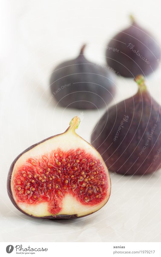 Four figs on a light background Fig Sliced Food fruit Vitamin Nutrition Vegetarian diet Fresh Healthy Violet Red White pseudo-fruit Studio shot Copy Space top