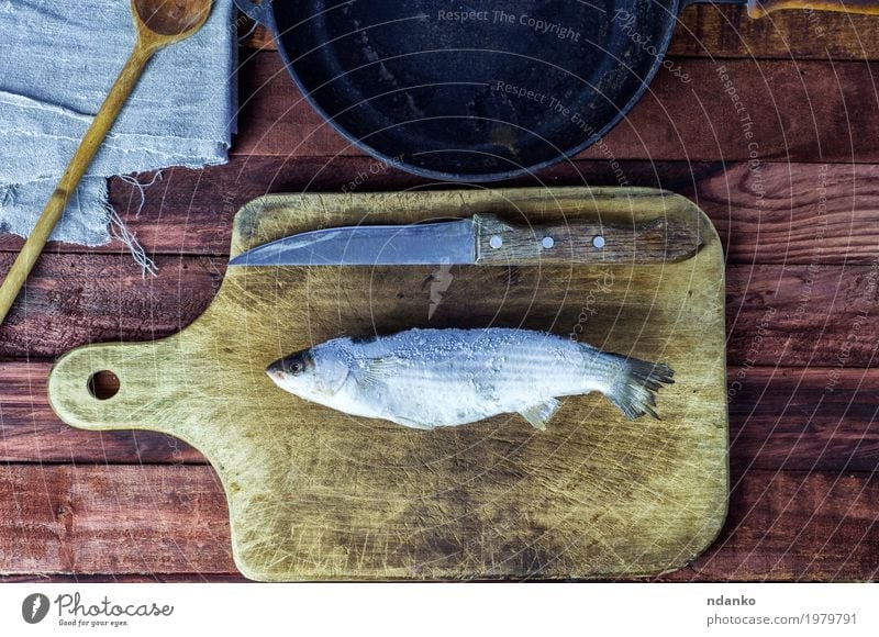 Frozen fish smelt on the kitchen board Food Fish Eating Knives Spoon Table Kitchen Wood Metal Fresh Natural Above Brown Black White whole Gourmet Top scale