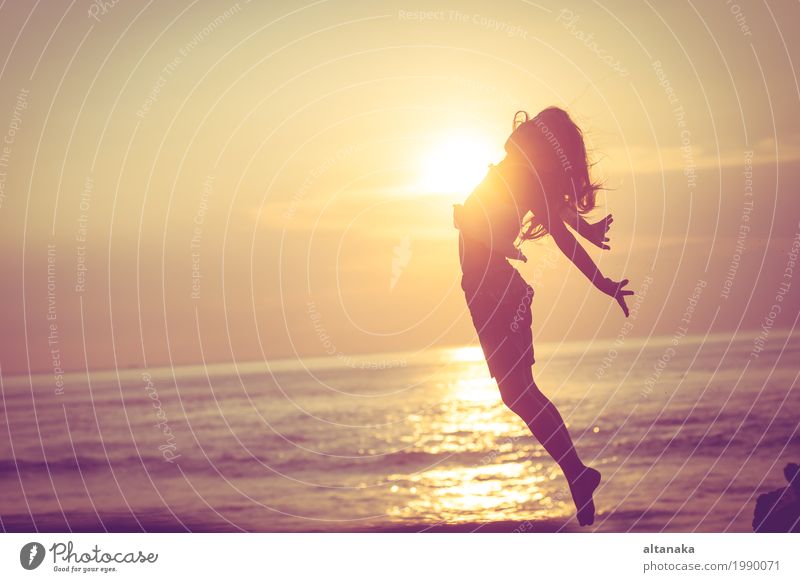 Happy little girl jumping on the beach at the sunset time Lifestyle Joy Leisure and hobbies Playing Vacation & Travel Trip Freedom Summer Sun Beach Ocean Sports