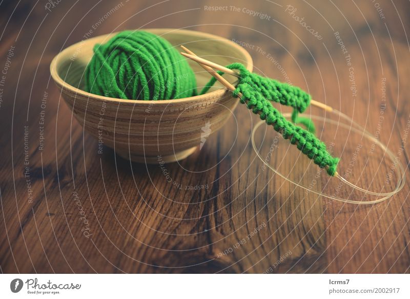 knitting with green wool in a bowl on wooden table. Design Leisure and hobbies Winter Warmth Fashion Wool Knit Creativity creased yarn craft Background picture