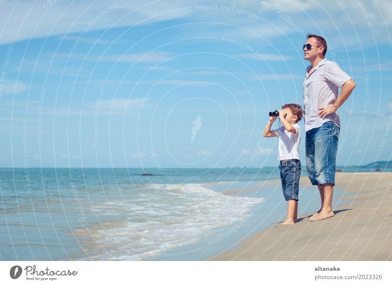Father and son with binoculars standing on the beach at the day time. Concept of friendly family. Lifestyle Joy Relaxation Leisure and hobbies Playing