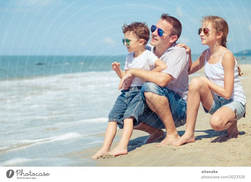 Father and children sitting on the beach at the day time. Concept of happy friendly family. Lifestyle Joy Relaxation Leisure and hobbies Playing