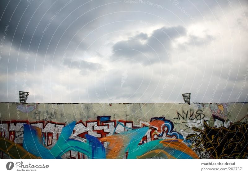 EAR Sky Clouds Bad weather Capital city Building Wall (barrier) Wall (building) Sign Characters Graffiti Threat Dirty Dark Cold Gloomy Youth culture Stadium