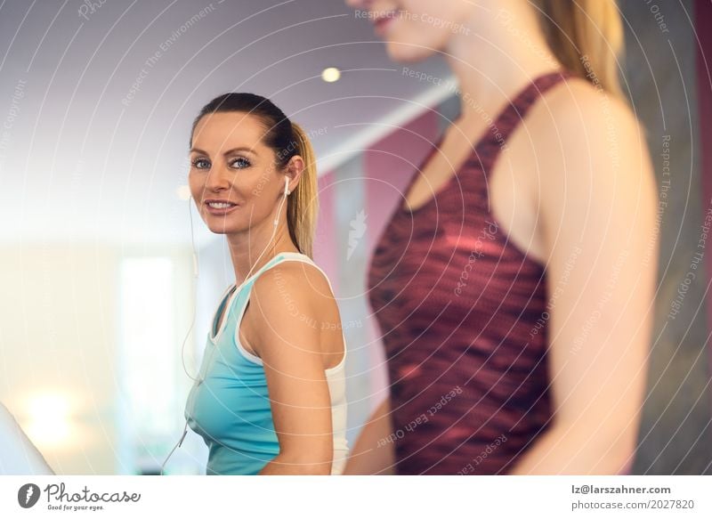 Attractive Woman with earphones on treadmill in the gym Lifestyle Happy Beautiful Face Leisure and hobbies Sports Adults 2 Human being 18 - 30 years
