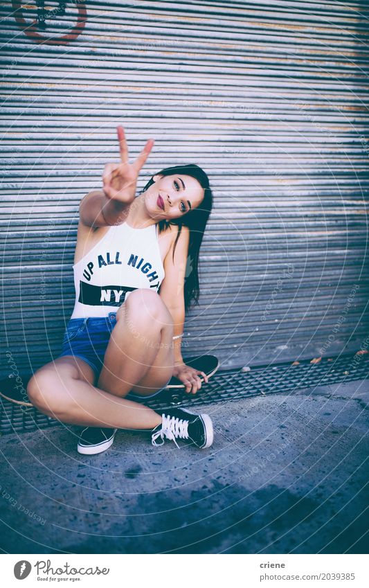 Young happy woman sitting on skateboard making peace hand sign Lifestyle Joy Leisure and hobbies Freedom Human being Feminine Young woman Youth (Young adults)