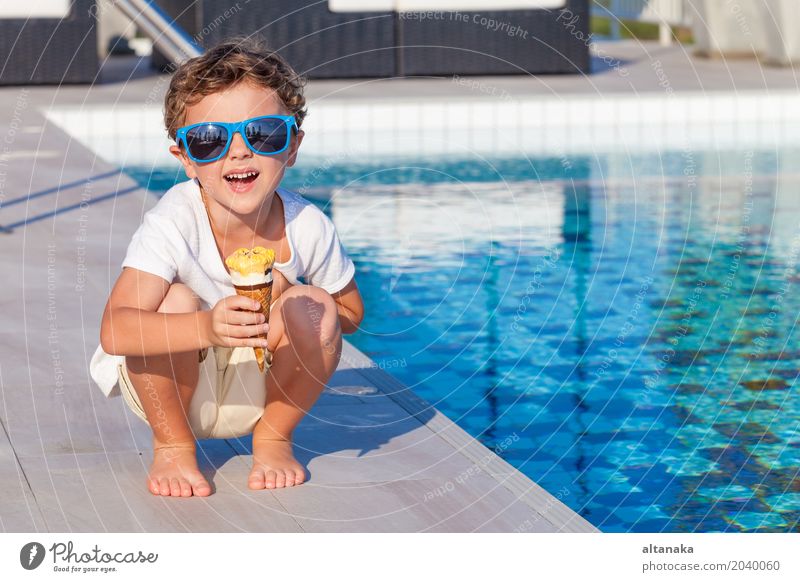 happy little boy with ice cream sitting near a swimming pool Dessert Eating Lifestyle Joy Happy Beautiful Relaxation Leisure and hobbies Playing