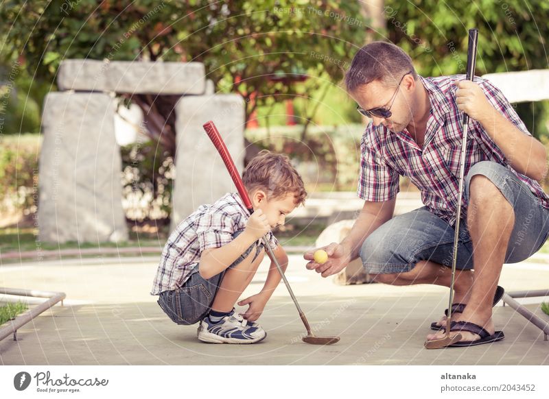 Cheerful young man teaching his son to play mini golf Lifestyle Joy Happy Relaxation Leisure and hobbies Playing Vacation & Travel Freedom Summer Sun Club Disco
