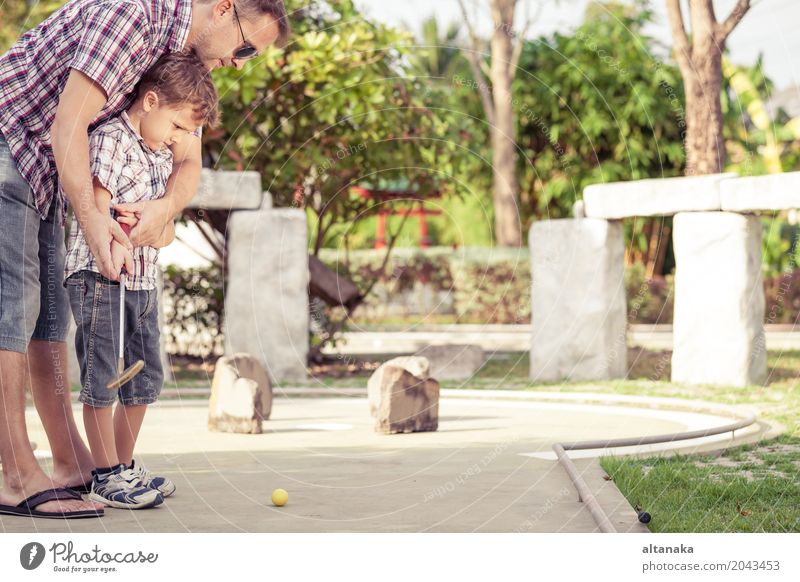 Cheerful young man teaching his son to play mini golf Lifestyle Joy Happy Relaxation Leisure and hobbies Playing Vacation & Travel Freedom Summer Sun Club Disco