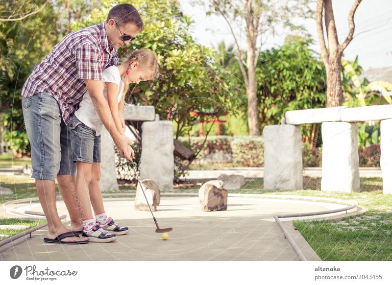 Cheerful young man teaching his daughter to play mini golf Lifestyle Joy Happy Relaxation Leisure and hobbies Playing Vacation & Travel Freedom Summer Sun Club