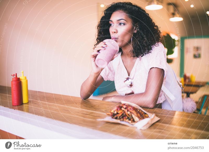 Young Afro American woman having milkshake and fries in bar Eating Lunch Dinner Fast food Drinking Lifestyle Restaurant Feminine Young woman