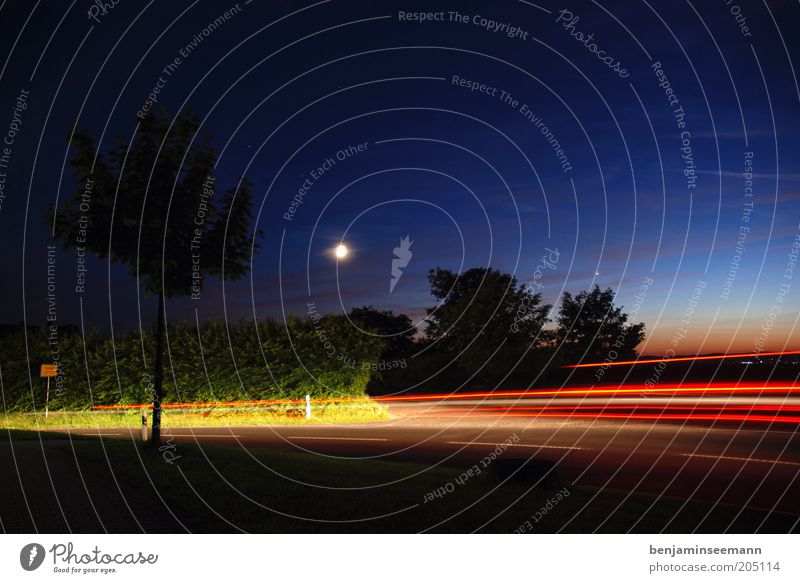 Blurred lights on a country road in front of a sunset. The moon in the sky. Sky Night sky Moon Traffic infrastructure Street Movement Town sign Car lights