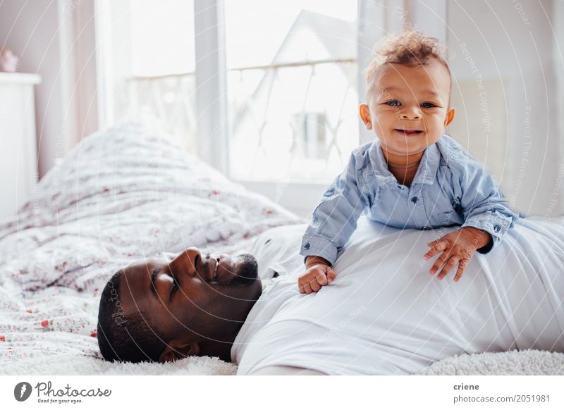 Young Afro-American dad and toddler cuddle together Lifestyle Joy Happy Bedroom Human being Masculine Baby Toddler Boy (child) Young man Youth (Young adults)
