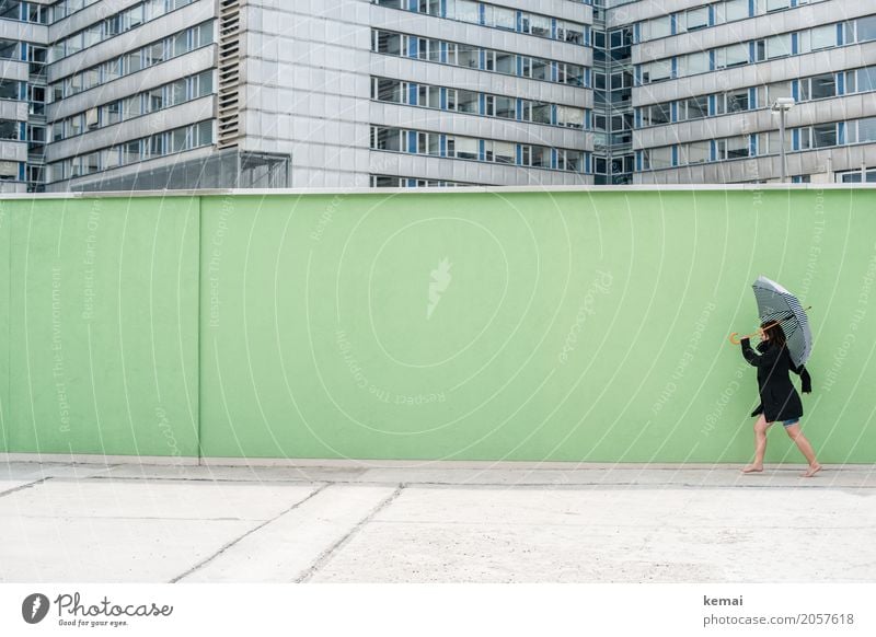 Woman with umbrella in front of a green wall, in the background skyscrapers Style Leisure and hobbies Playing Trip Freedom City trip Wall (building)