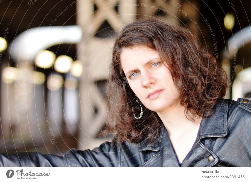 cool young woman with black leather jacket stands in front of steel girders in an underpass and looks confidently into the camera Human being Feminine