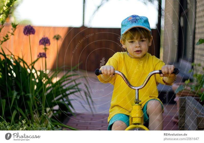 Child on a tricycle Human being Toddler Boy (child) Face 1 1 - 3 years Nature Summer Garden Authentic Cap T-shirt naturally Curiosity Yellow Infancy