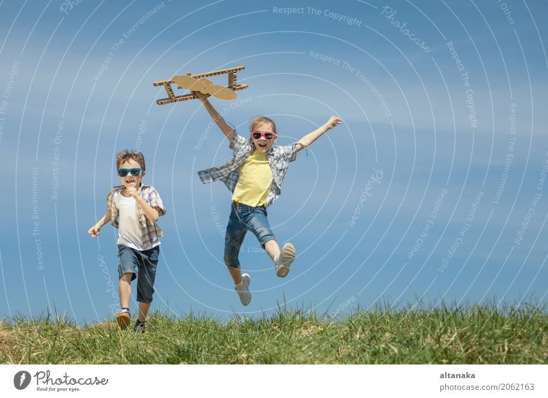 Two Little Kids Playing With Cardboard Toy Airplane In The Park At The Day Time Concept Of Happy Game Child Having Fun Outdoors Picture Made On The Background Of Blue Sky