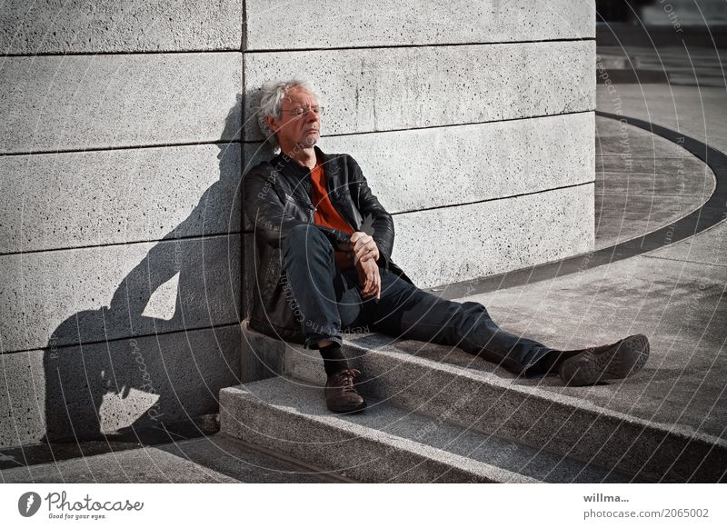 In the shadow of himself Man Eyeglasses White-haired Curl Sit rest Break Relaxation Concrete wall Shadow Masculine Human being Adults urban Rest Restful