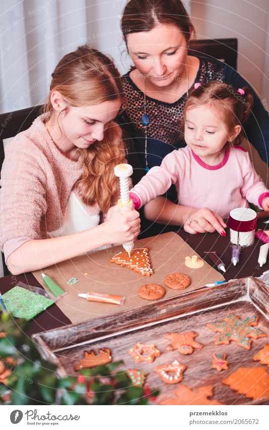 Family decorating baked Christmas gingerbread cookies with frosting Decoration Table Kitchen Feasts & Celebrations Child Human being Woman Adults