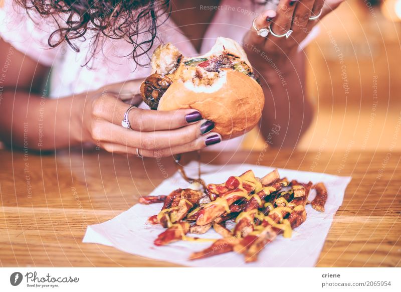 Close-up of woman eating fries and Hamburger Meat Bread Roll Herbs and spices Eating Diet Fast food Lifestyle Restaurant Woman Adults Afro Fat Delicious Joy