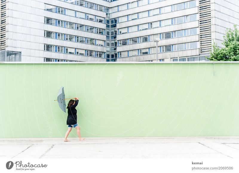 Woman with umbrella in front of a green wall, in the background skyscrapers Lifestyle Harmonious Leisure and hobbies Trip Freedom Human being Feminine Adults 1