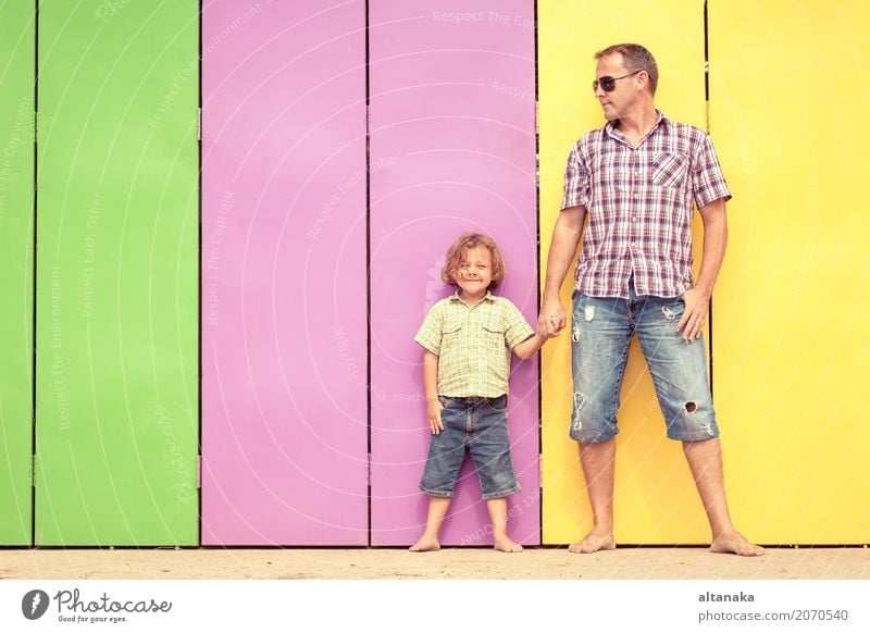 Father and son relaxing near the house at the day time. They standing near are the colorful wall. Concept of friendly family. Lifestyle Joy Happy Relaxation