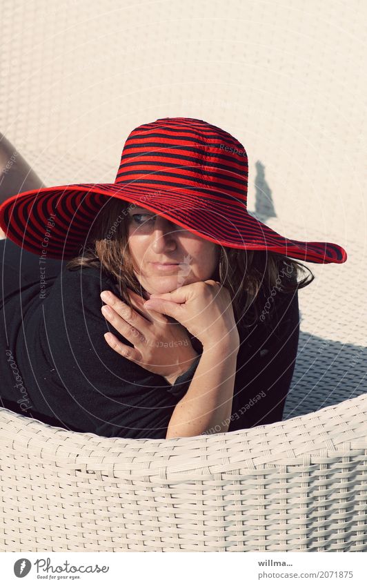 Woman with red hat lies on white wicker couch and enjoys the sun Human being Feminine Adults Life Summer Hat Relaxation Sunbathing Lady portrait Looking away