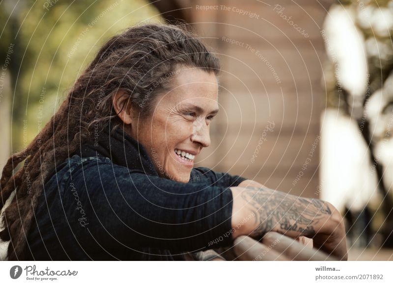 Tattooed young woman with dreadlocks smiles mischievously Young woman Youth (Young adults) rastas Laughter contented Easygoing Long-haired Dreadlocks Happiness