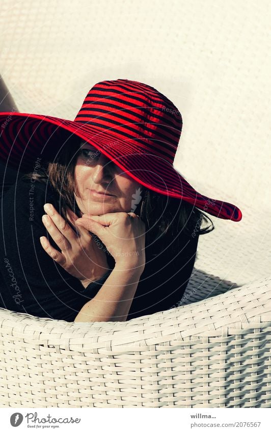 Lady with red hat lies watching on white wicker couch in the sun Lifestyle Elegant Harmonious Well-being Contentment Relaxation Summer Summer vacation