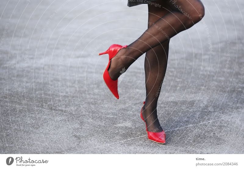 Beautiful woman legs wearing red heels over grey - Stock Image