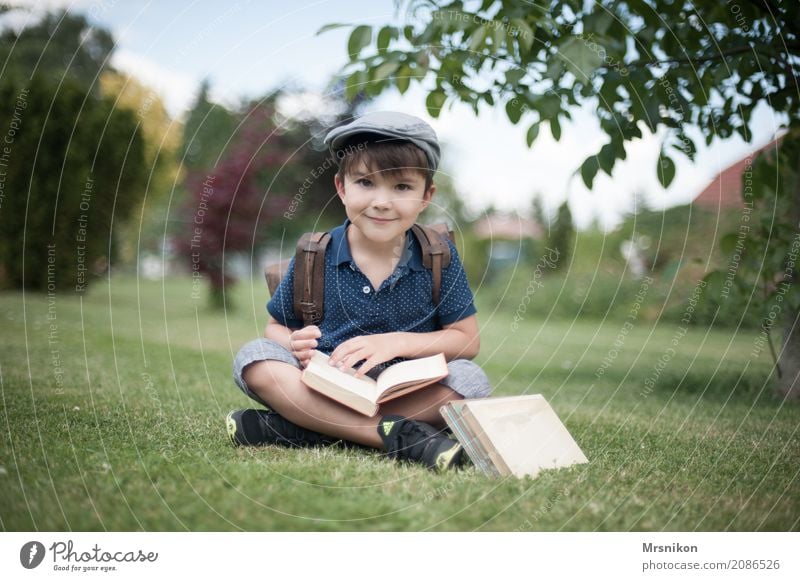 enrolment Human being Child Boy (child) Infancy Life 1 3 - 8 years Smiling Study Sit Cap First day at school Book Ancient Satchel Meadow Garden Exterior shot
