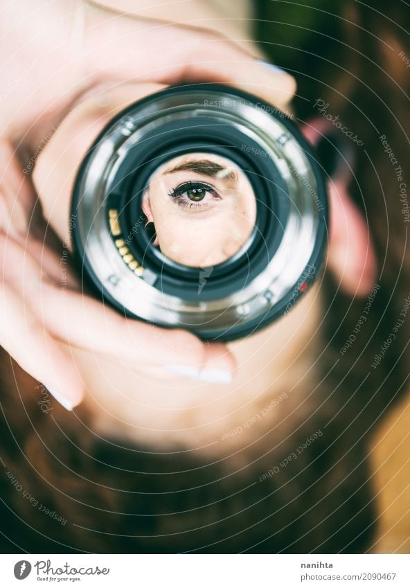 Young woman s eye looking  through  a camera lens a 