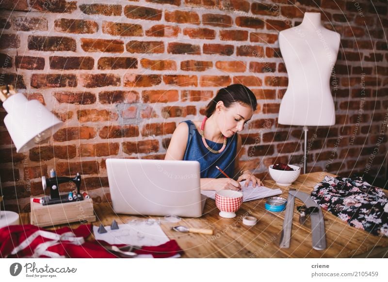 Young female fashion designer working at desk in office Reading Desk Work and employment Office work Business SME Technology Human being Feminine Young woman