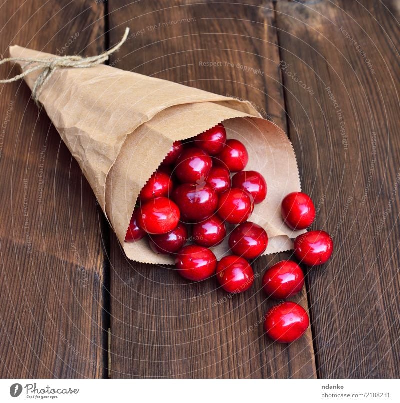 Ripe red cherry in a paper bag Fruit Dessert Eating Vegetarian diet Juice Summer Table Nature Paper Wood Fresh Natural Above Retro Juicy Red background Berries
