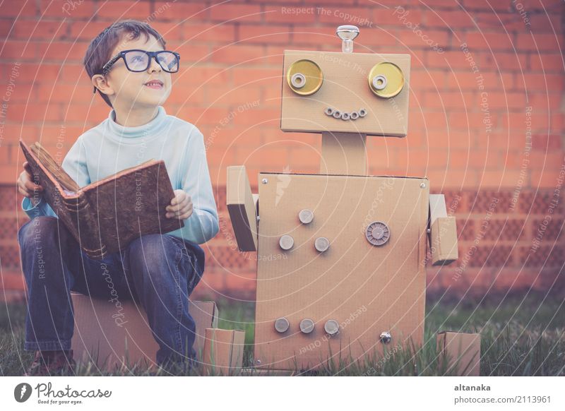 One little boy reading to robot from cardboard boxes outdoors. Concept of science and education. Lifestyle Joy Happy Beautiful Relaxation Leisure and hobbies