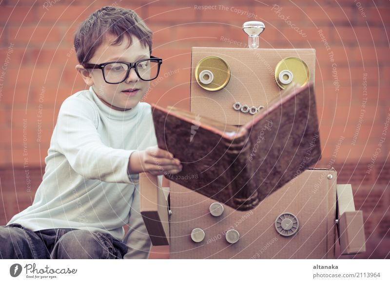 One little boy reading to robot from cardboard boxes outdoors. Concept of science and education. Lifestyle Joy Happy Beautiful Relaxation Leisure and hobbies
