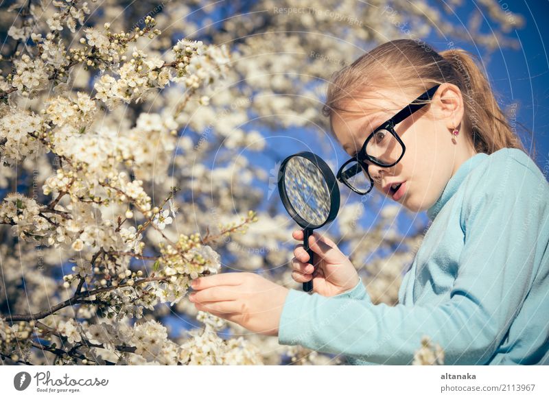 Happy little girl exploring nature with magnifying glass at the day time. Concept of interesting lesson. Lifestyle Joy Face Relaxation Playing Summer Garden