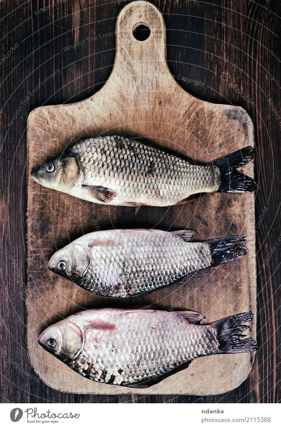 Three fresh river fish carp Fish Eating Diet River Wood Retro Brown crucian food three kitchen board cook Live vintage Edible scales whole Tasty Top cooking Raw