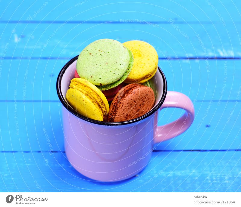 Almond biscuit macaron in a mug Dessert Candy Cup Mug Table Gastronomy Wood Bright Delicious Above Blue Brown Yellow Green Pink Tradition colorful background