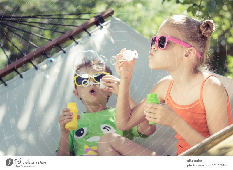 Two happy children lie on a hammock and play with soap bubbles. Lifestyle Joy Happy Beautiful Relaxation Leisure and hobbies Playing Freedom Camping Summer Sun