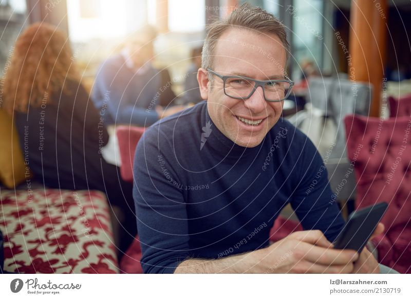 Attractive man sitting in a restaurant Restaurant Business Telephone Cellphone PDA Man Adults 1 Human being 30 - 45 years Eyeglasses Smiling Sit Thin attractive