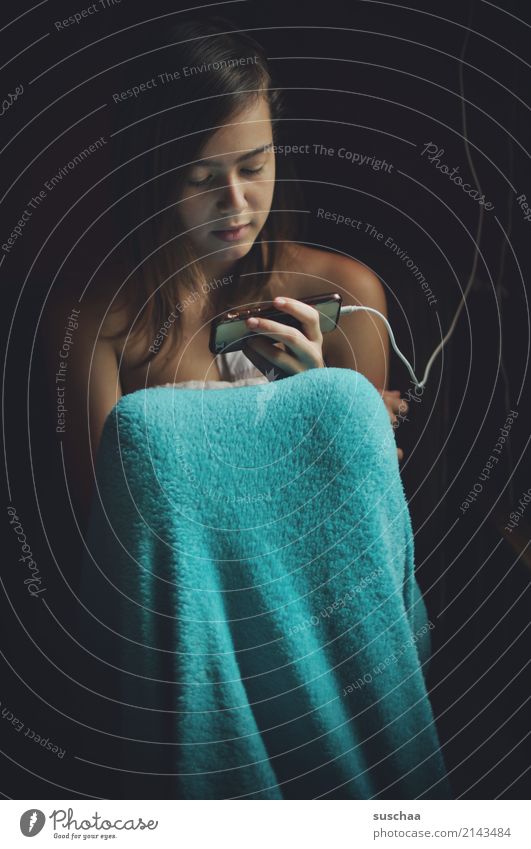 girl sits wrapped in a blanket and looks into her smartphone Child Youth (Young adults) Young woman 13 - 18 years Internet Telephone SMS social media Face