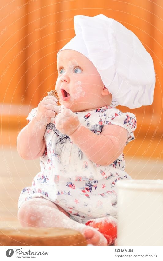 A cute little girl in chef's hat sitting on the kitchen floor soiled with flour, playing with food, making a mess and having fun Food Cake Eating Lifestyle Joy