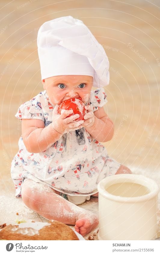 A cute little girl in chef's hat sitting on the kitchen floor soiled with flour, playing with food, making a mess and having fun Eating Lifestyle Joy Feminine